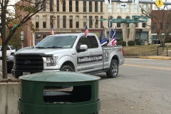 A truck with multiple American flags and one black and white American flag with a blue stripe is parked across from the Putnam County Courthouse.