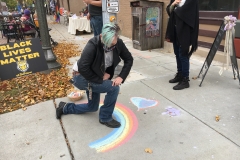 J.D. Grove looks down at a chalk rainbow on the sidewalk.
