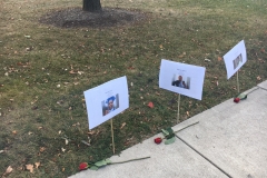 A closer shot shows three of the signs with the roses by them. The names are not legible