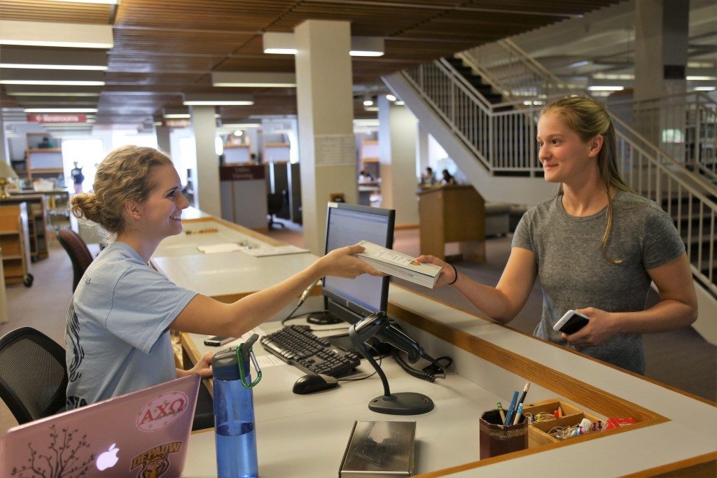Library Assistant, Emily Fox, is helping freshman, Lydia Thibault, to get a book for her first-year class. SON LE / THE DEPAUW