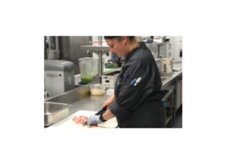 A chef cuts a slab of meat as she works in Hoover's kitchen, located in the basement-NATALIE BRUNINI