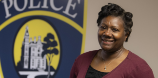 DePauw University Chief of Police smiles in front of a painted logo for the university's Police Department.