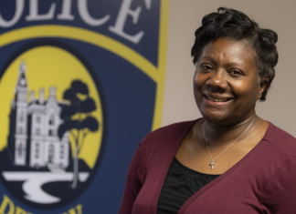 DePauw University Chief of Police smiles in front of a painted logo for the university's Police Department.