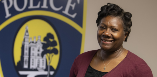 DePauw University Chief of Police smiles in front of a painted logo for the university's Police Department.