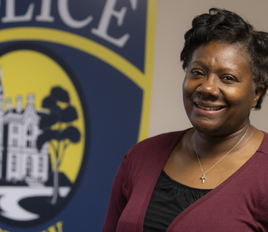 DePauw University Chief of Police smiles in front of a painted logo for the university's Police Department.