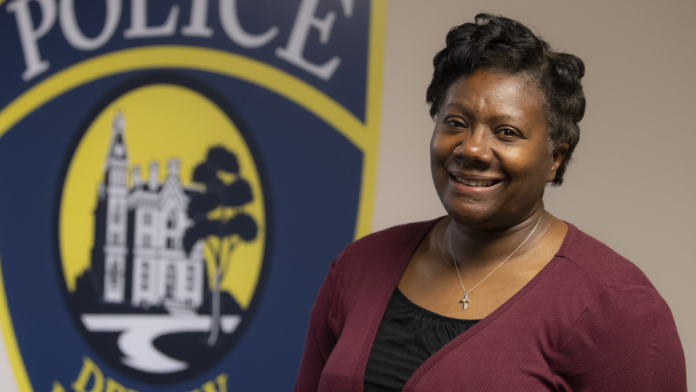 DePauw University Chief of Police smiles in front of a painted logo for the university's Police Department.